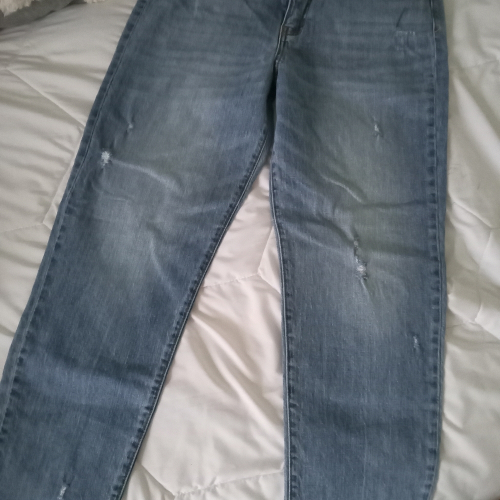 Distressed denim jeans. Light blue denim. Loose fit, greying at bottom.